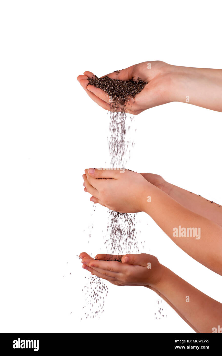 Chia seeds falling from woman's  hand to children's hands. Isolated over white. Stock Photo