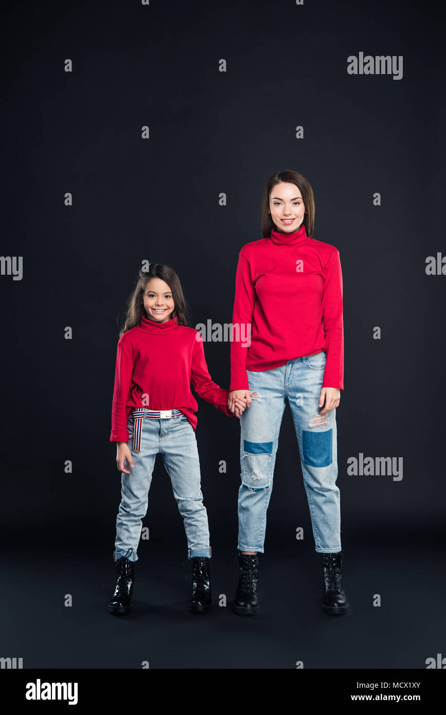 Mother and daughter standing and holding hands isolated on black Stock ...