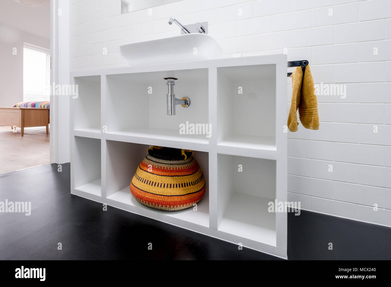 Contemporary white painted MDF bathroom unit, with colourful Bolga basket and black vinyl