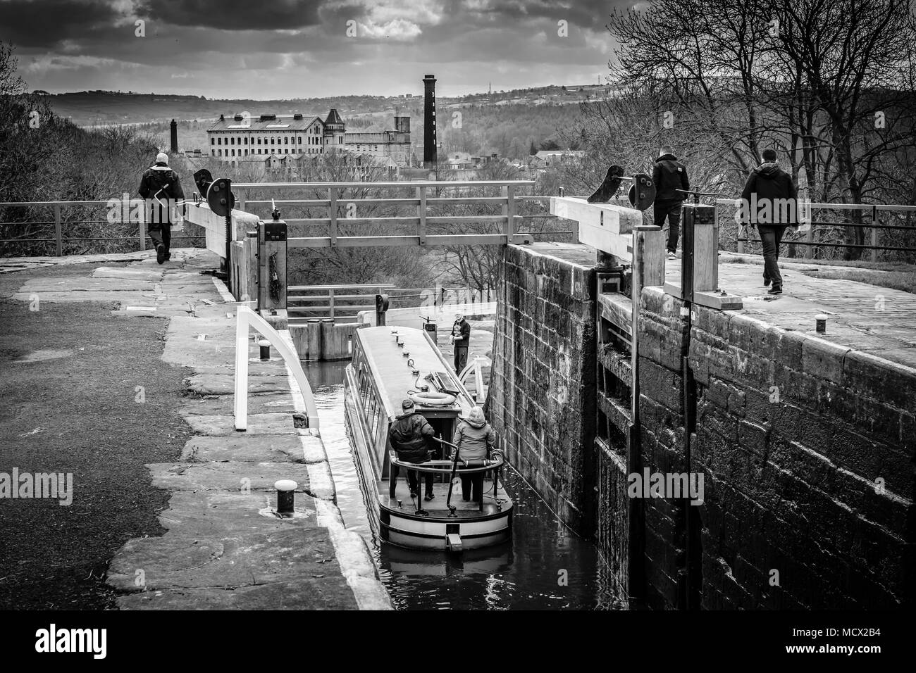 A boat being lowered down The Five Rise Locks on the Leeds and Liverpool Canal, Bingley, near Bradford, West Yorkshire, England. Stock Photo