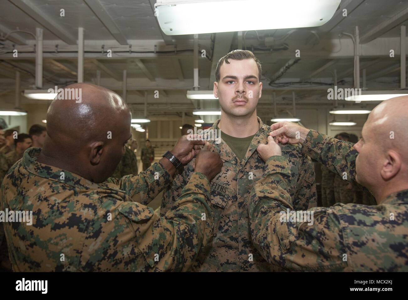 U.S. Marine Corps Cpl. Tyler D. Griffiths, center, a cryptologic linguist with the 26th Marine Expeditionary Unit (MEU), is promoted to the rank of Sergeant by Sgt. Maj. Jeffrey A. Young, left, the sergeant major of the 26th MEU, and Col. Farrell J. Sullivan, the commanding officer of the 26th MEU, during a promotion ceremony aboard the Wasp-class amphibious assault ship USS Iwo Jima (LHD 7), Mar. 1, 2018. The 26th MEU is deployed at sea to conduct maritime security operations, crisis response and theater security cooperation, while also providing a forward expeditionary naval presence in Euro Stock Photo