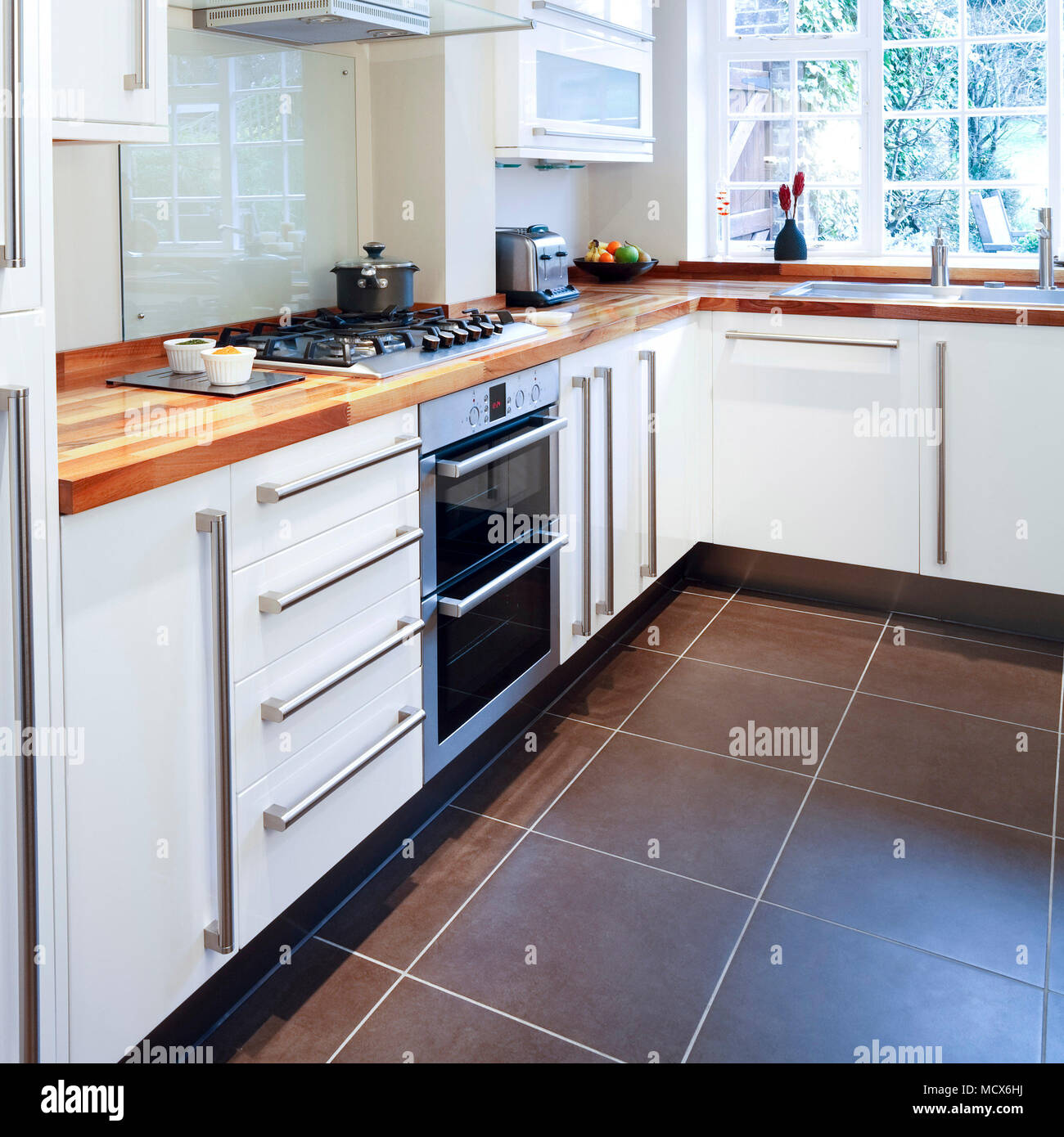 Modular white kitchen with wooden worktops and stainless steel appliances Stock Photo