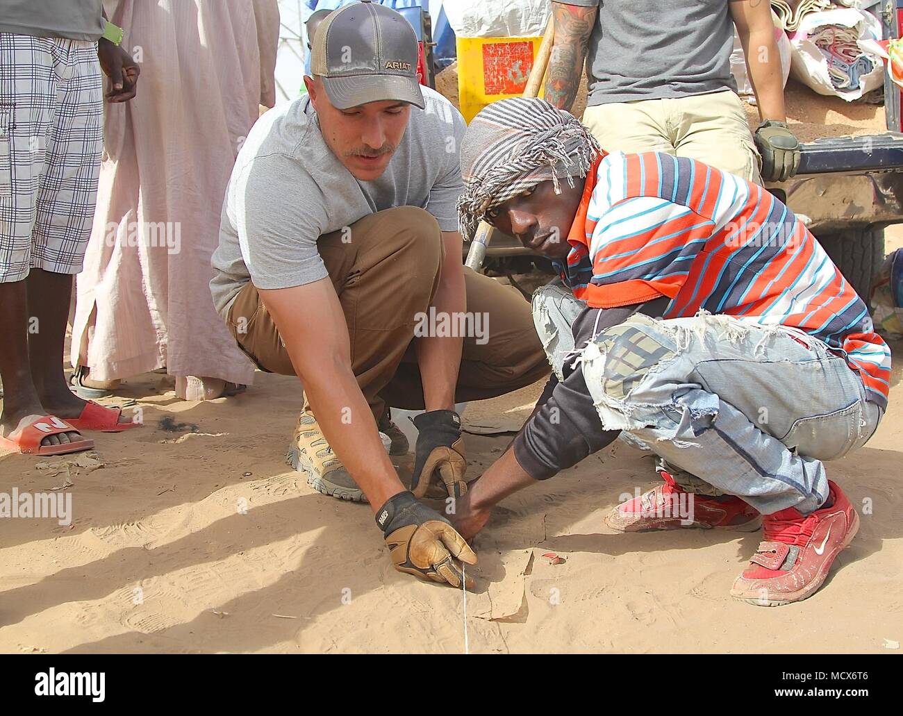 Service members of Task Force Darby teach Cameroonian community leaders the Do-Nou road construction method. Do-Nou is a low-cost, high labor method to create a sub-base for unimproved roads. SSgt. Jesse Brand (left), and other Army and Air Force service members, provide assistance with the hands-on training. TF Darby serve members are serving in a support role for the Cameroonian Military’s fight against the violent extremist organization Boko Haram. Stock Photo