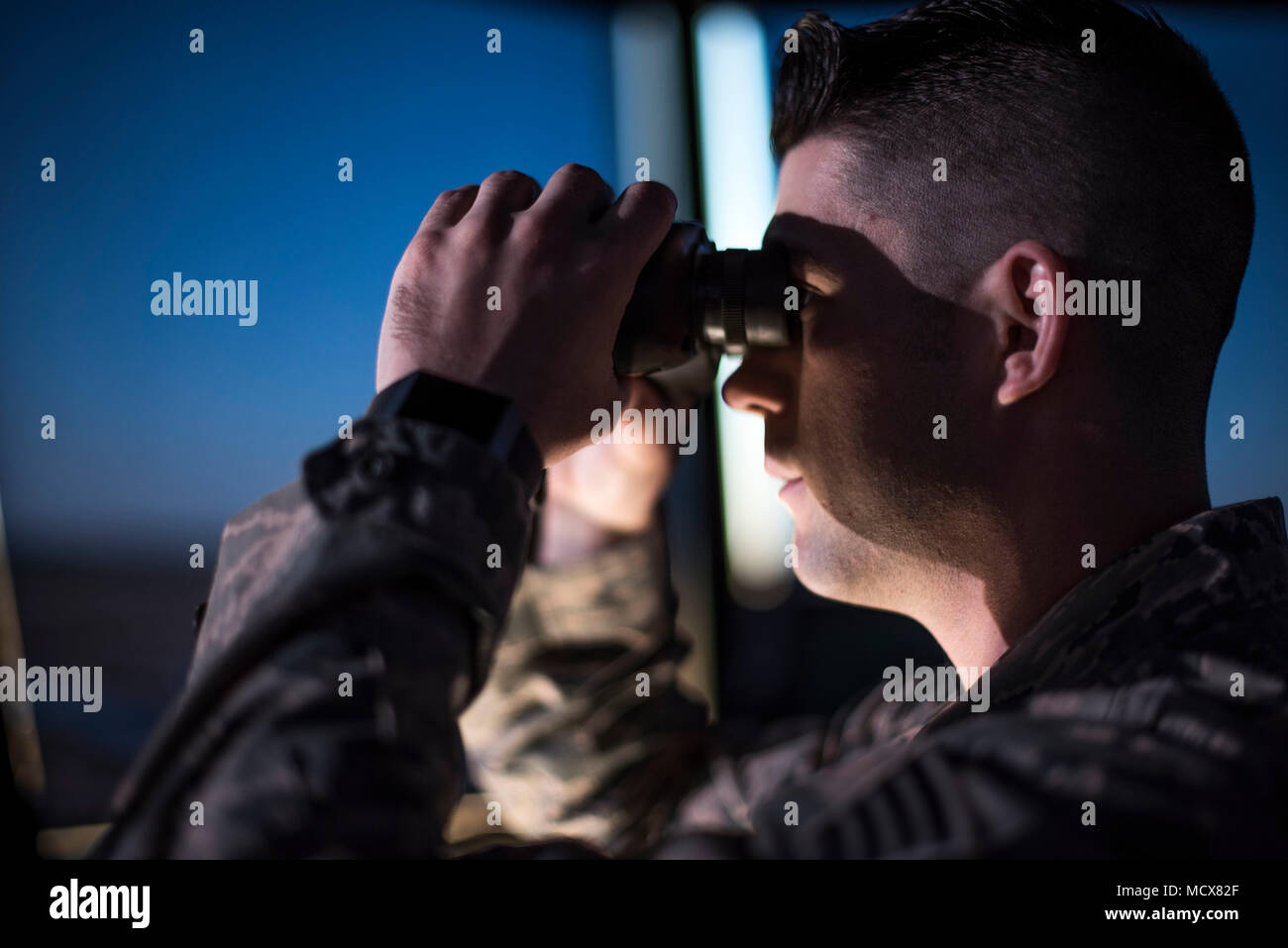 SSgt Chase Kelly, an air traffic controller, looks out over the Vance Air Force Base flightline using binoculars, March 1, 2018. Air traffic controllers use binoculars as a tool to help them see greater distances. (U.S. Air Force photo by Airman Zachary Heal) Stock Photo