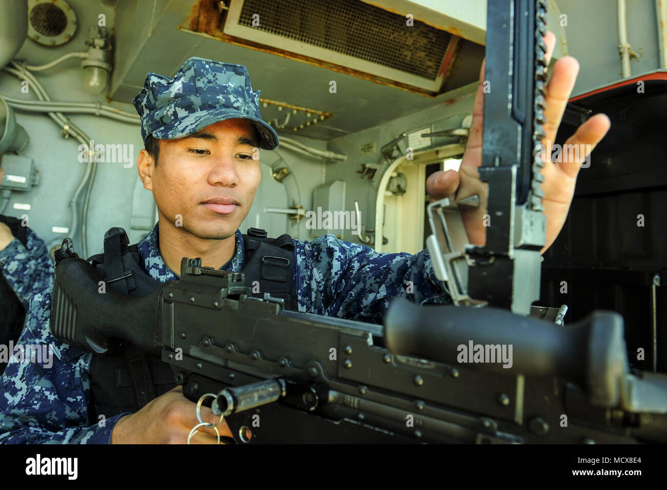 180302-N-ZS023-017 NAVAL BASE SAN DIEGO (March 2, 2018) Aviation Ordnanceman Airman Sean Aldan, a native of Santa Rita, Guam, assigned to the amphibious assault ship USS America (LHA 6), inspects an M240B machine gun on one of the ship’s catwalks as the ship departs Naval Base San Diego. America is getting underway off the coast of southern California preparing for an ammunitions offload prior to entering a routine maintenance availability period. (U.S. Navy photo by Mass Communication Specialist 3rd Class Vance Hand/Released) Stock Photo