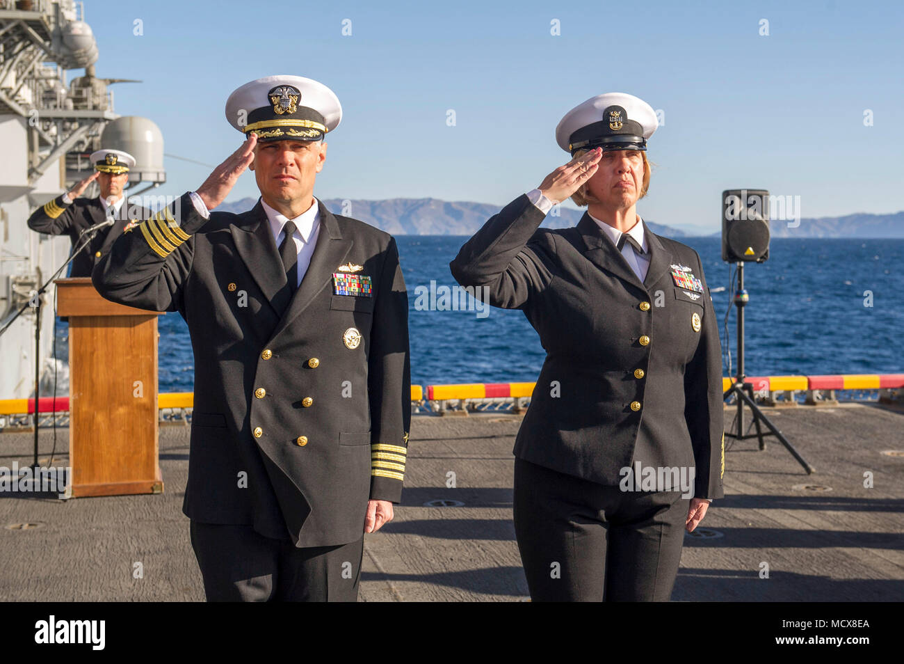 180304-N-ZS023-035 PACIFIC OCEAN (March 4, 2018) Capt. Joseph Olson, commanding officer of the amphibious assault ship USS America (LHA 6), and Command Master Chief Sandra Dyal, render honors during a burial-at-sea ceremony on the ship’s starboard elevator. America is underway off the coast of southern California preparing for an ammunitions offload prior to entering a planned maintenance availability period. (U.S. Navy photo by Mass Communication Specialist 3rd Class Vance Hand/Released) Stock Photo