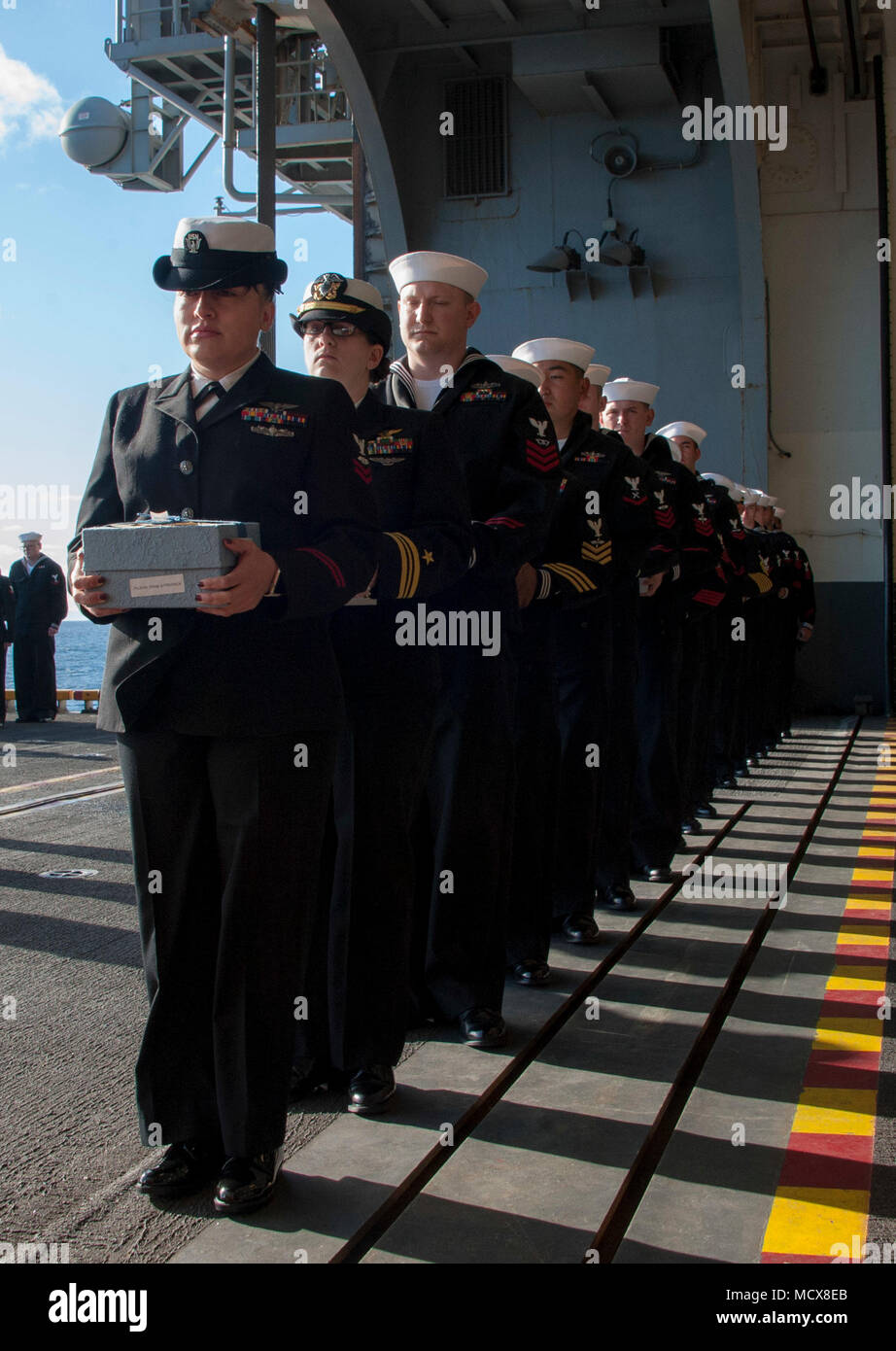 180304-N-HT134-035  PACIFIC OCEAN (March 4, 2018) Sailors assigned to the amphibious assault ship USS America (LHA 6) participate in a burial-at-sea ceremony on the ship’s starboard elevator. America is underway off the coast of southern California preparing for an ammunitions offload prior to entering a planned maintenance availability period. (U.S. Navy photo by Mass Communication Specialist Seaman Daniel Pastor/Released) Stock Photo