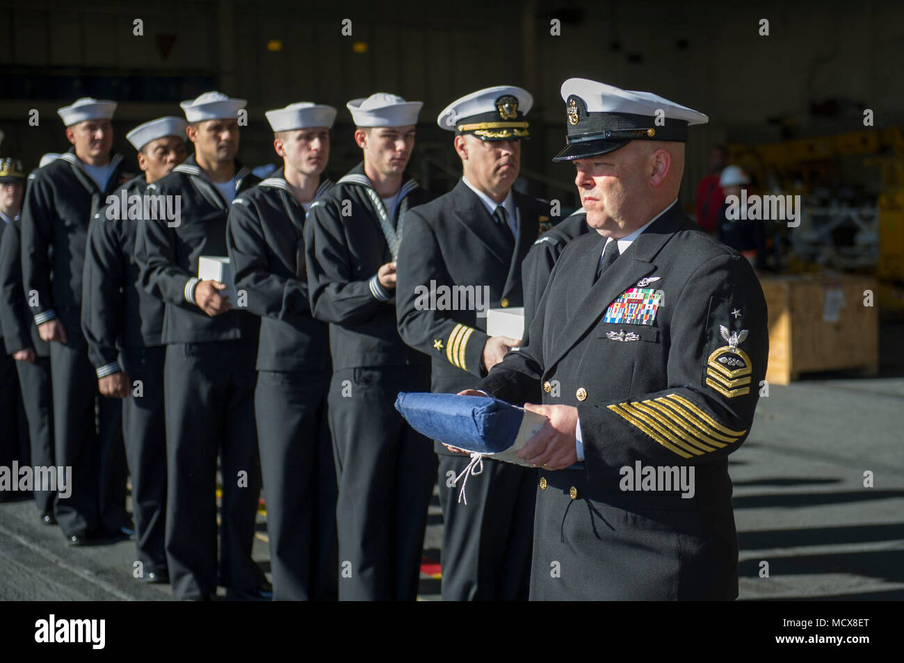 180304-N-ZS023-050 PACIFIC OCEAN (March 4, 2018) Senior Chief Aviation Boatswain’s Mate (Fuel) William Harrison, a native of Lincoln City, Oregon, assigned to the amphibious assault ship USS America (LHA 6), carries remains during a burial-at-sea ceremony on the ship’s starboard elevator. America is underway off the coast of southern California preparing for an ammunitions offload prior to entering a planned maintenance availability period. (U.S. Navy photo by Mass Communication Specialist 3rd Class Vance Hand/Released) Stock Photo