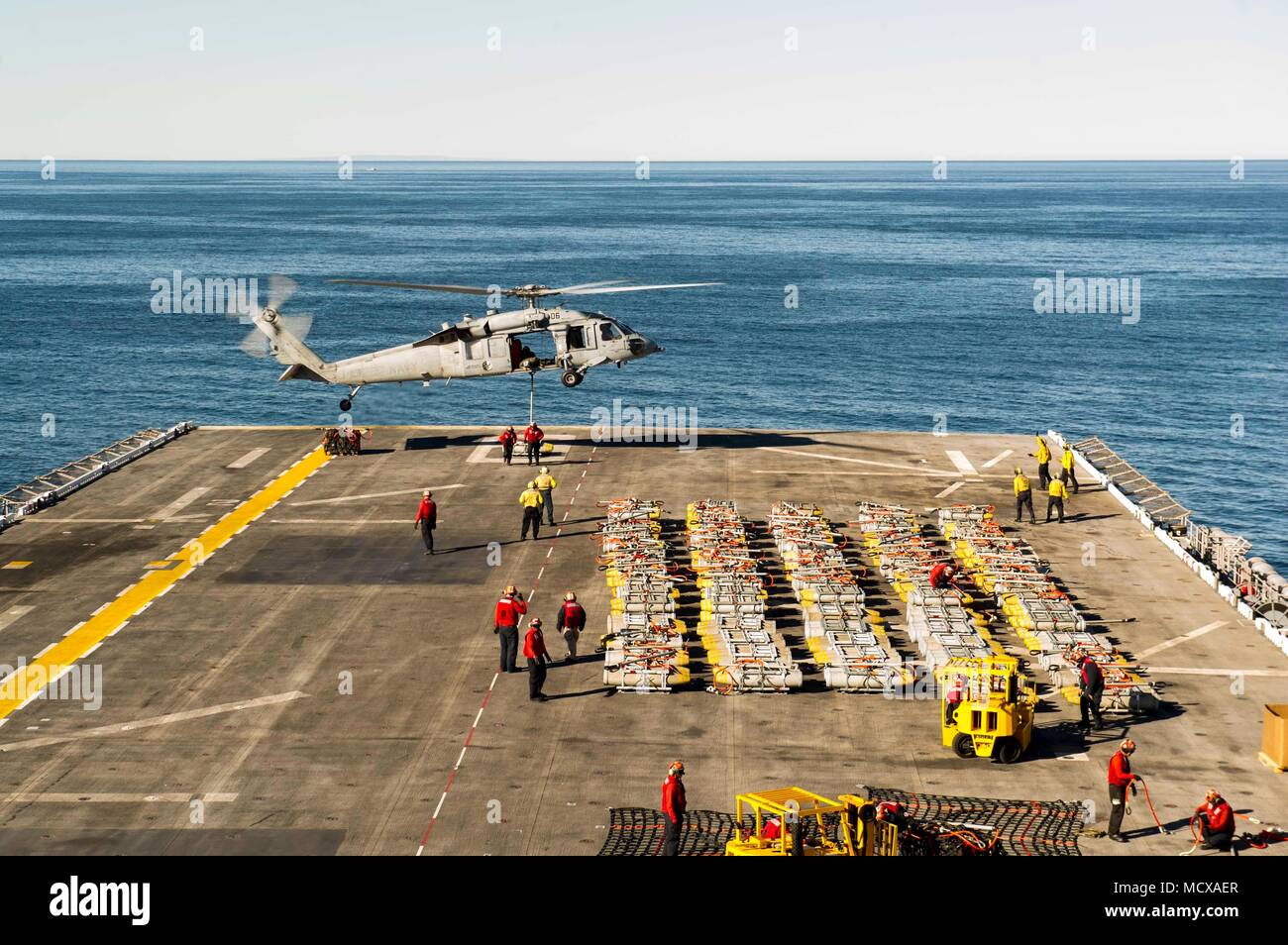 180305-N-ZS023-003  PACIFIC OCEAN (March 5, 2018) Sailors assigned to the amphibious assault ship USS America (LHA 6) attach ordnance to an MH-60S Sea Hawk helicopter assigned to the “Wildcards” of Helicopter Sea Combat Squadron (HSC) 23 on the flight deck. America is underway off the coast of southern California conducting an ammunitions offload prior to entering a planned maintenance availability period. (U.S. Navy photo by Mass Communication Specialist 3rd Class Vance Hand/Released) Stock Photo