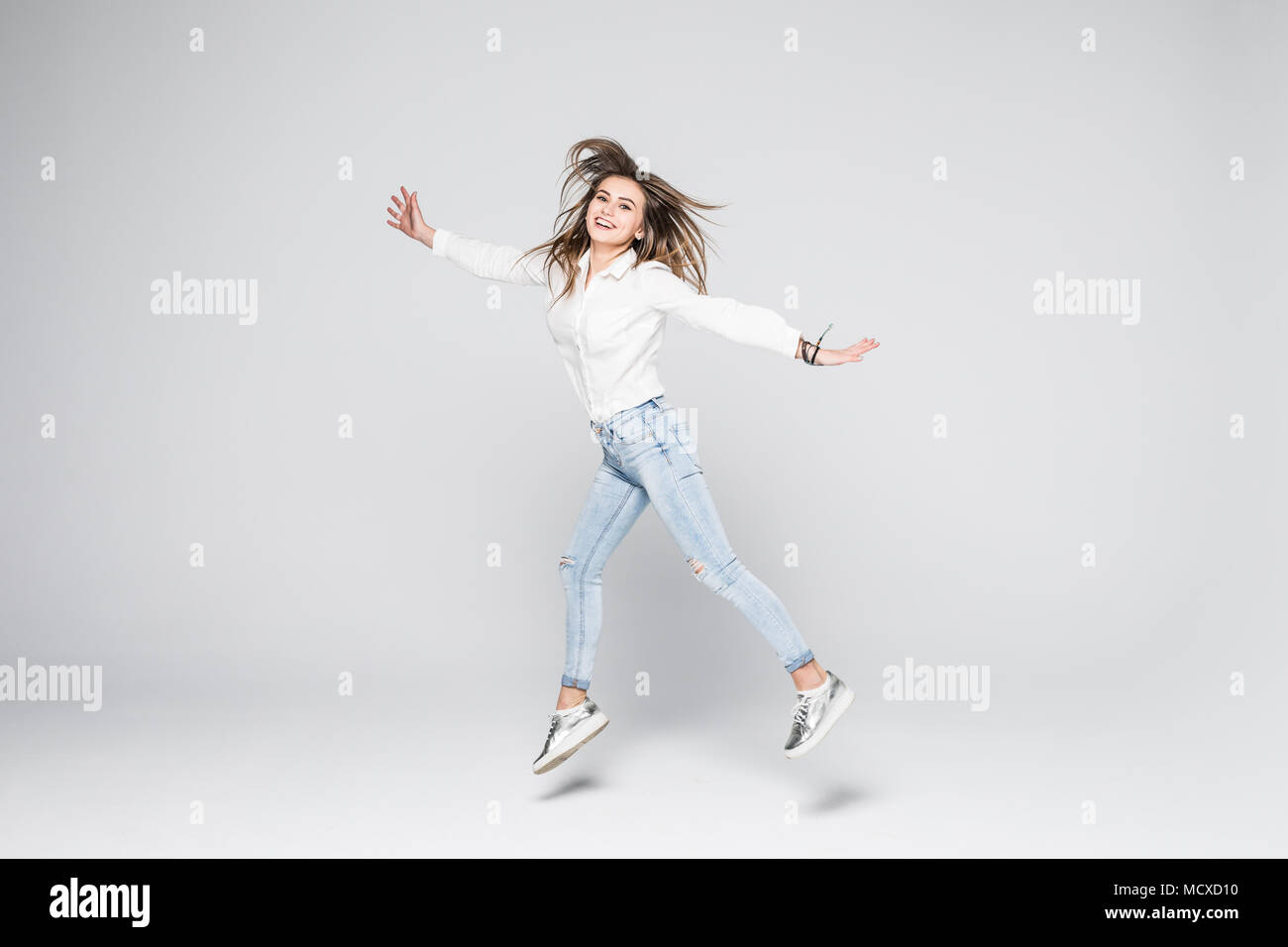 Full length portrait of a cheerful cute woman jumping isolated on a ...
