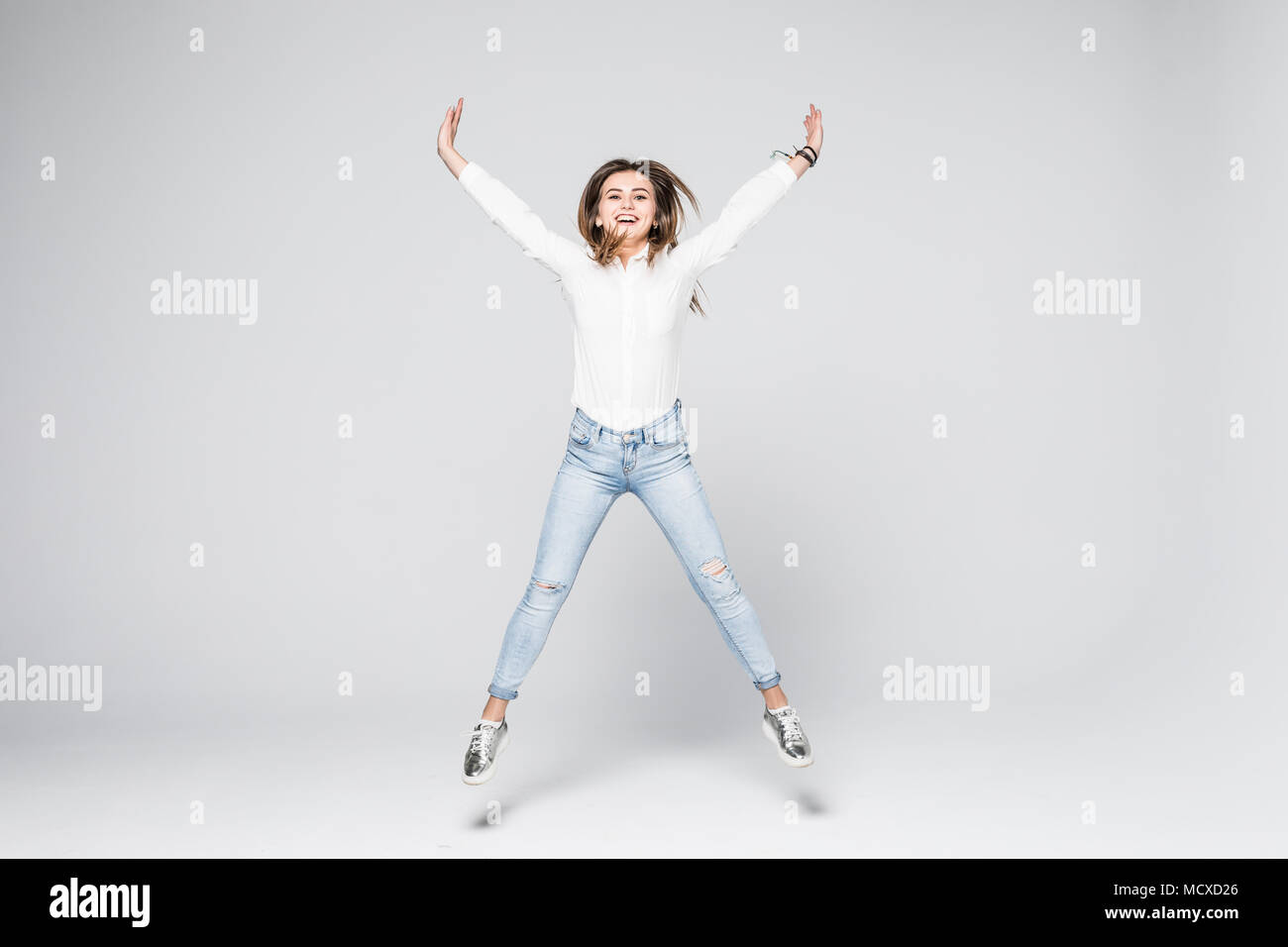 Full length portrait of a young beautiful brunette girl jumping and ...