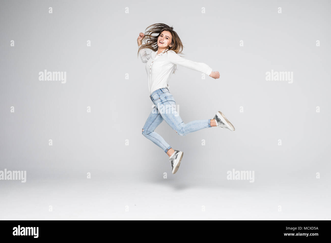 Full length portrait of a cheerful cute woman jumping isolated on a ...