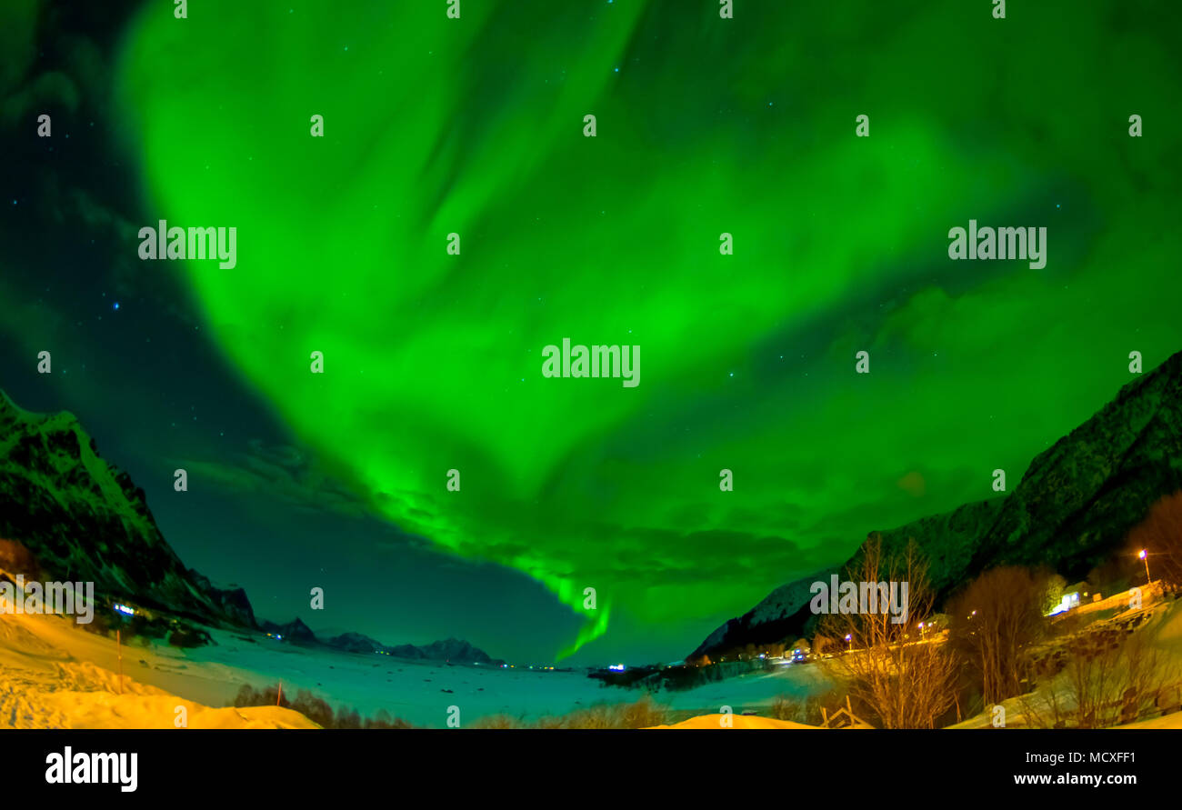 Northern lights shine bright and beautiful above sharp peaks and lakes of Lofoten mountains Stock Photo