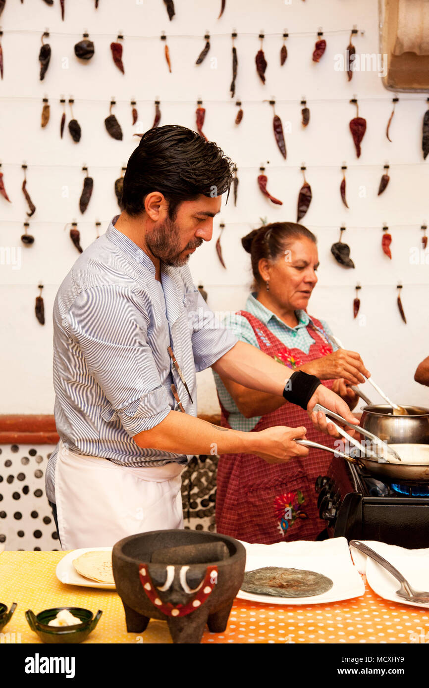 Chef José Luis Diaz and his mother cooking enchiladas de san pedro totolapam (meat-filled tortillas with chile sauce) with him  Restaurante Chilhuacle Stock Photo