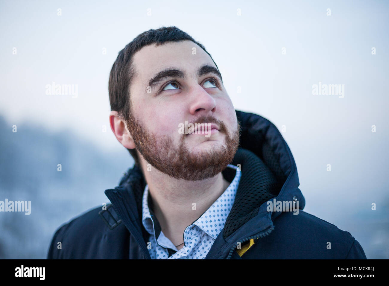 Portrait of a young dreaming happy man looking up at blue sky Stock Photo