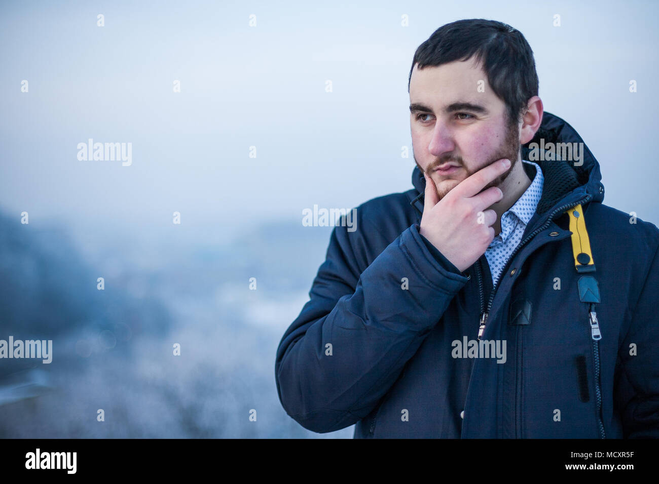 Portrait of a young concentrated man keeping hand on chin making decision Stock Photo