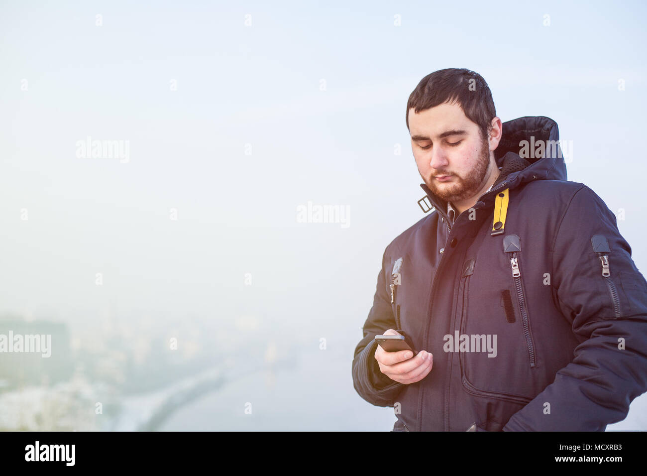 Man traveler using cellphone against winter cityscape Stock Photo
