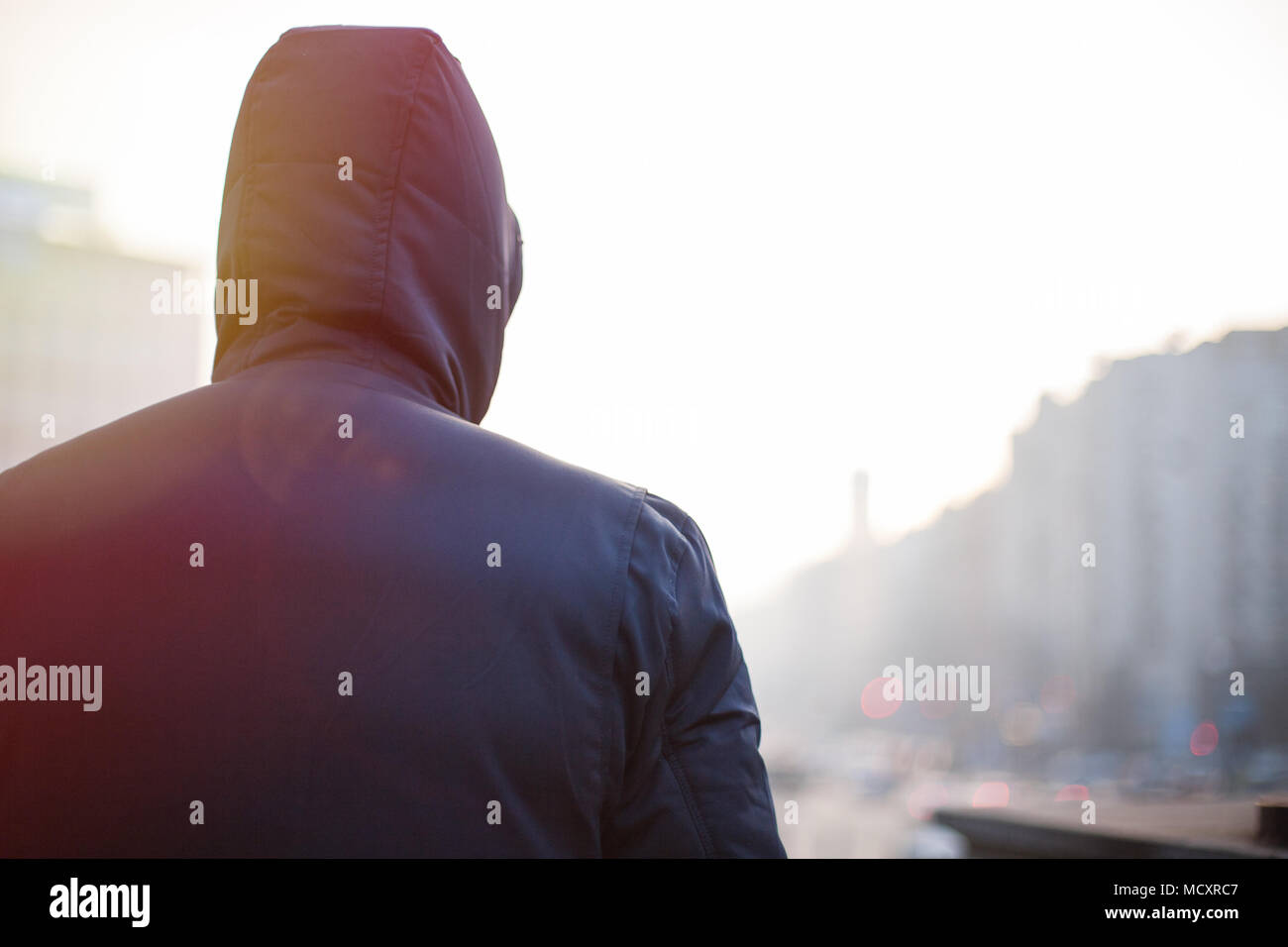 Lonely hipster man in hood walking on city street in the evening Stock Photo