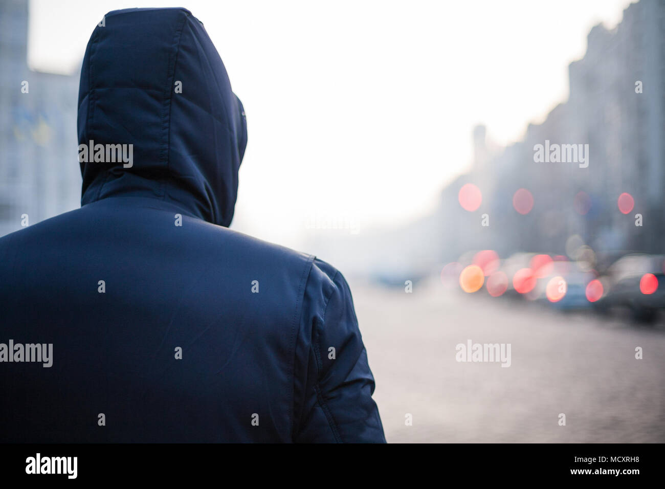 Hipster man in hood walking on city street Stock Photo