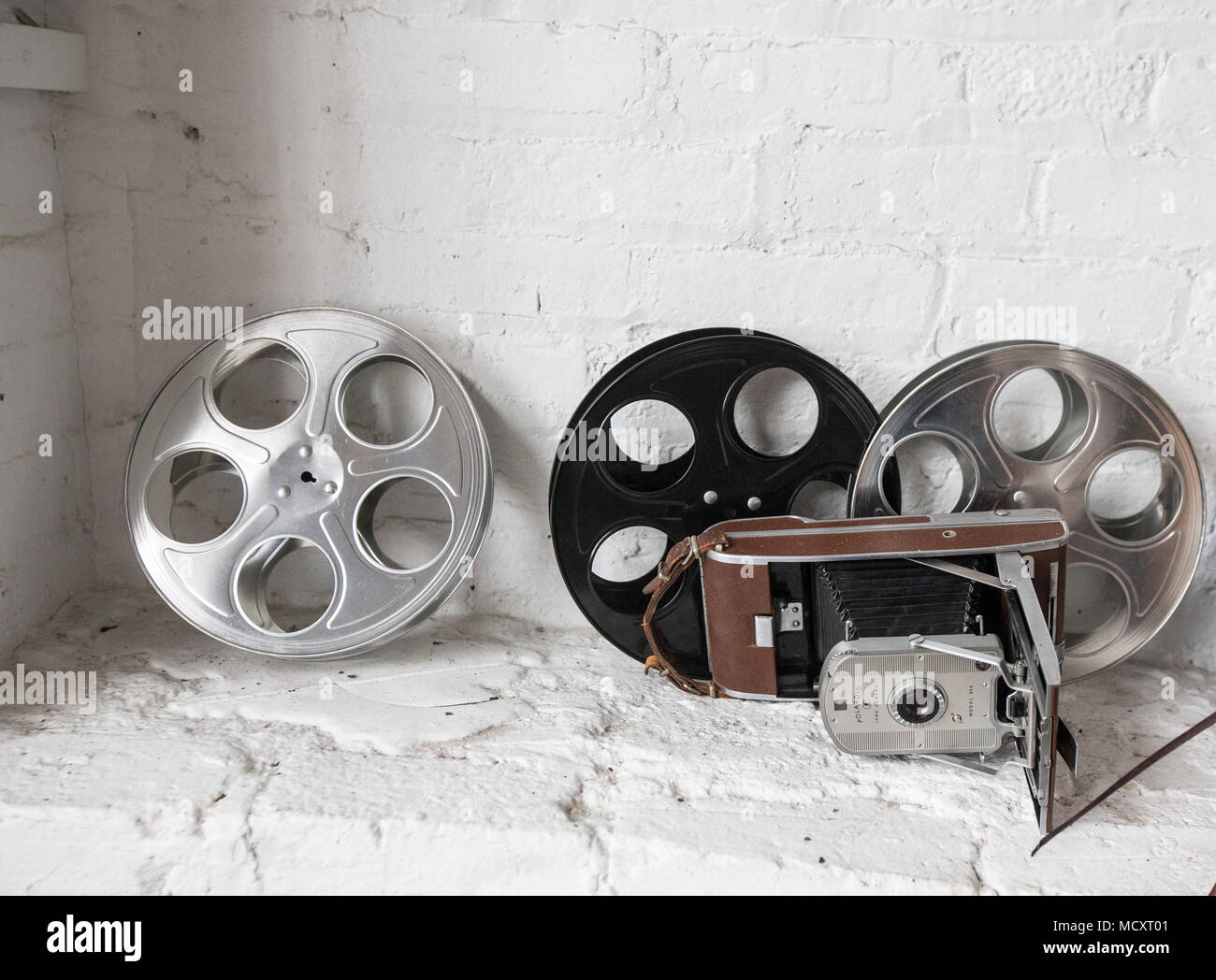 Film reels and a Polaroid camera on a shelf Stock Photo