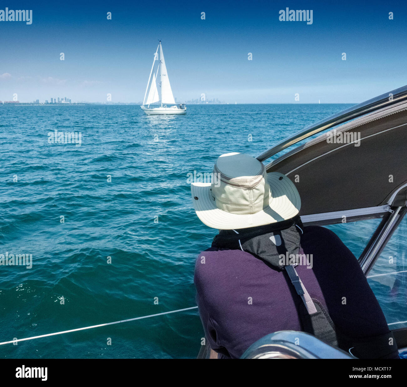 Man looking at sailboat in middle of the sea, Toronto, Canada Stock Photo