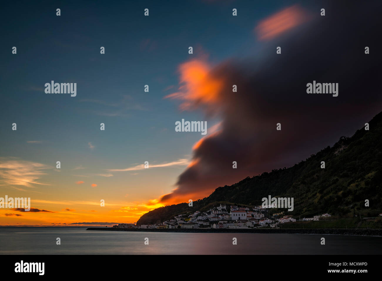 Small village by the sea, sunset with dramatic clouds behind mountain ridges, Ribeira Quente, Sao Miguel, Azores, Portugal Stock Photo