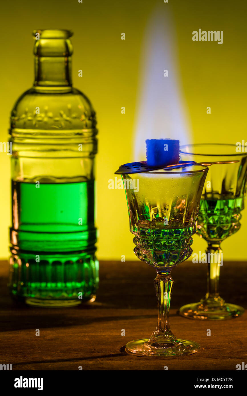 Bottle of absinthe and glasses with burning cube brown sugar. Stock Photo