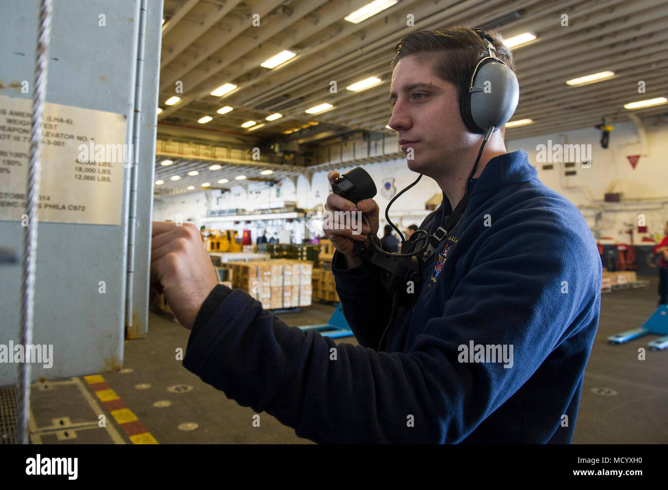 180306-N-ZS023-028 PACIFIC OCEAN (March 6, 2018) Aviation Ordnanceman Airman Jonah Getz, a Phoenix native, assigned to the amphibious assault ship USS America (LHA 6), communicates with the flight deck using a sound-powered telephone before transporting ordnance using the hangar bay elevator. America is underway off the coast of southern California conducting an ammunitions offload prior to entering a planned maintenance availability period. (U.S. Navy photo by Mass Communication Specialist 3rd Class Vance Hand/Released) Stock Photo