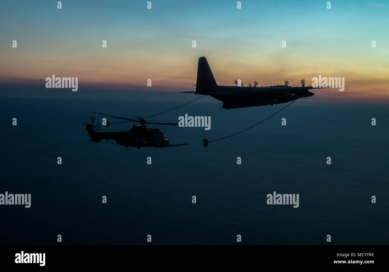 A NATO Air Force EC-725 Super Cougar prepares to receive fuel from a U.S. Air Force C-130 Hercules as part of Emerald Warrior over the Gulf of Mexico March 2, 2018. At Emerald Warrior, the largest joint and combined special operations exercise, U.S. Special Operations Command forces train to respond to various threats across the spectrum of conflict. (U.S. Air Force photo by Staff Sgt. Trevor T. McBride) Stock Photo