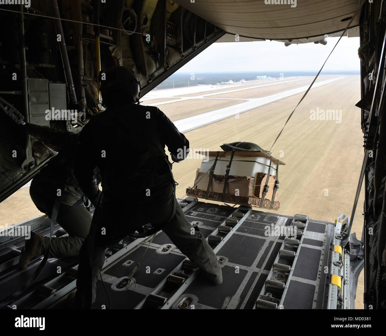 U.S. Air Force Senior Airman Joshua May (left) and Staff Sgt. Zachary  Sidders, loadmasters with the 182nd Airlift Wing, Illinois Air National  Guard, release a low-cost, low-altitude (LCLA) delivery bundle over the