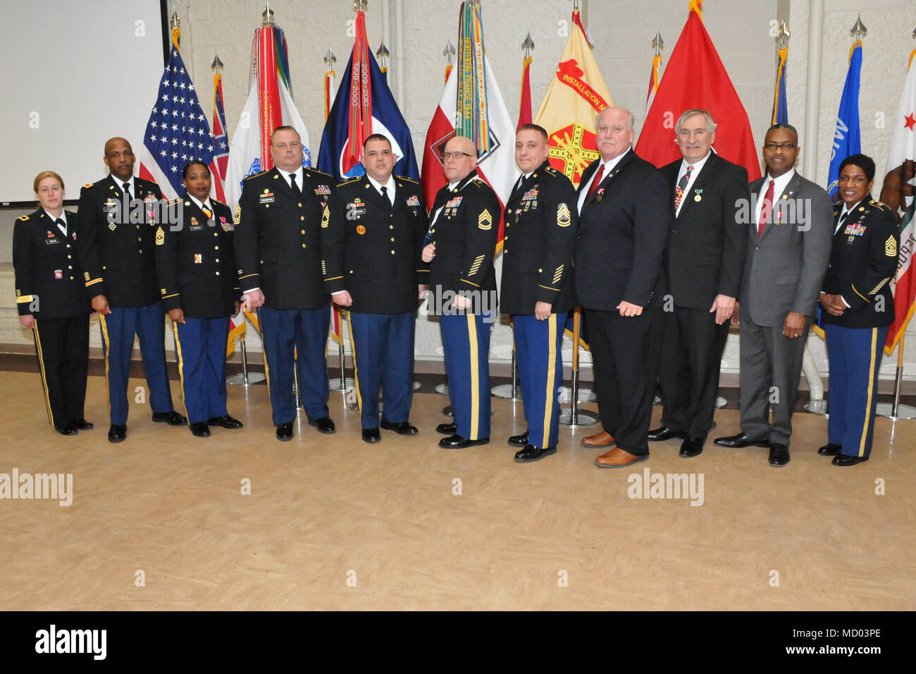 Nine retirees stand for a group photo following the quarterly Rock Island  Arsenal Retirement and Retreat Ceremony, March 8. From left to right: Brig. Gen. Heidi Hoyle, commanding general, JMC; retirees: Chief Warrant Officer 5 Alston Cleary, Sgt. Maj. Cherrie Parrish, 1st Sgt. Gary Friedrickson, Master Sgt. William Cintron-Flores, Sgt. 1st Class Dennis Shepard, Sgt. 1st Class Larry Weckherlin, Mark Clark, David House and Rickey Peer; and Command Sgt. Maj. Tomeka O'Neal, JMC. (Photo by: Tony Lopez, JMC Public and Congressional Affairs) Stock Photo