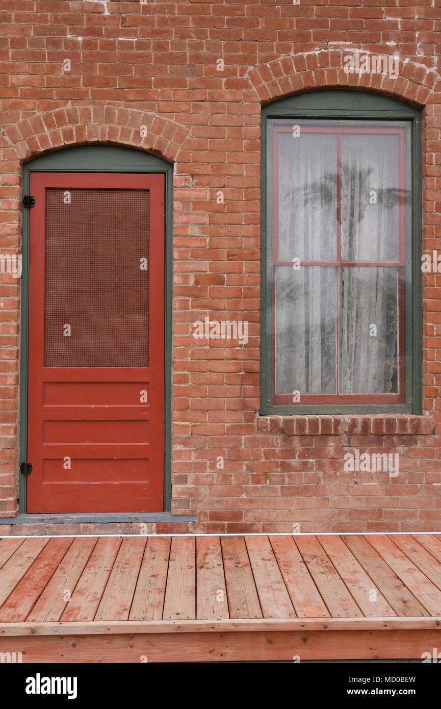Red door and window on old brick house with wood deck Stock Photo - Alamy