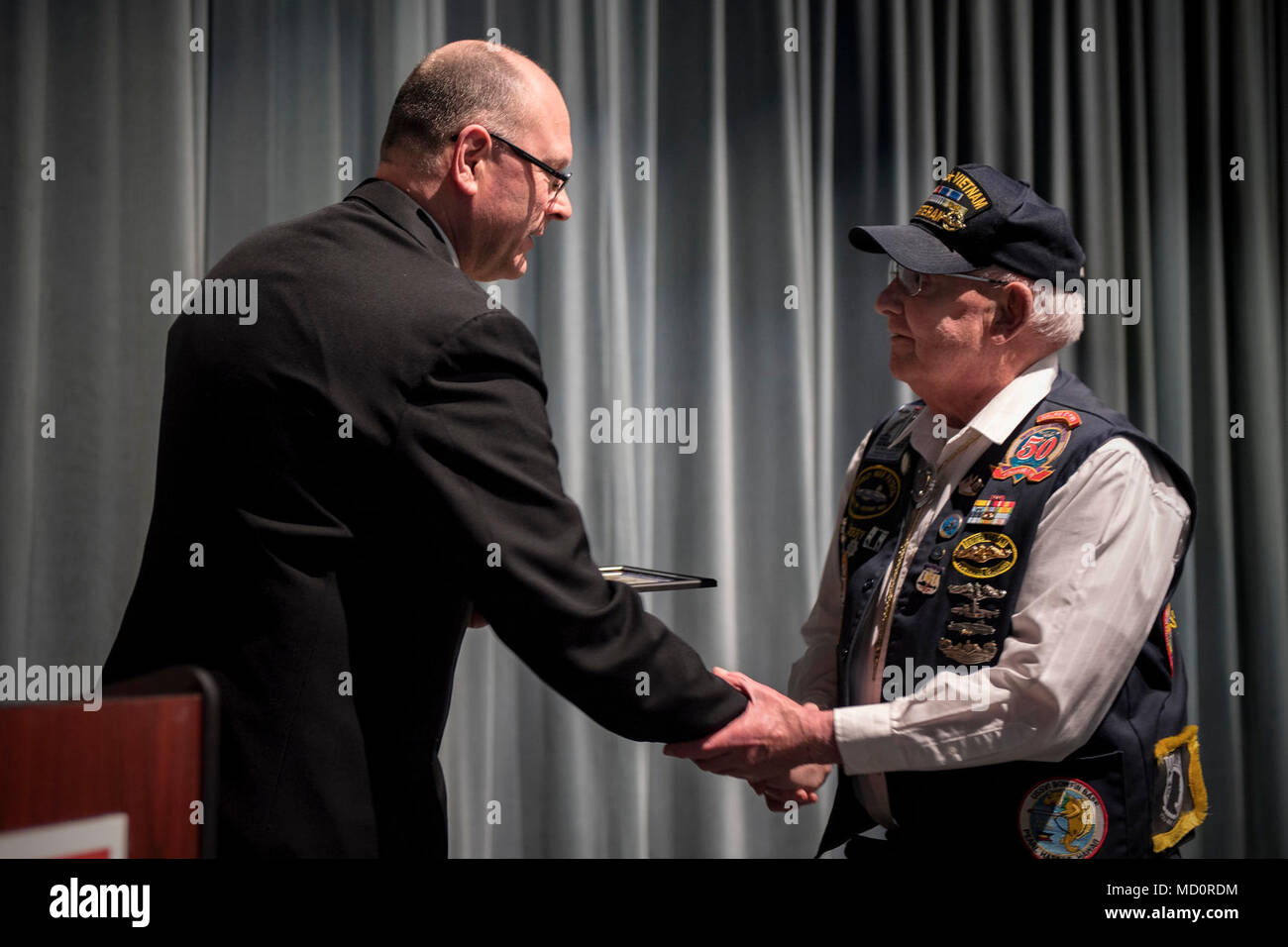 KEYPORT, Wash. (Mar. 29, 2018) Navy Region Northwest Command Master Chief Ted Calcaterra, left, presents a certificate and lapel pin to Gerald Drumm, from Bremerton, Wash., during a Vietnam veterans commemoration event recognizing the 50th anniversary of the Vietnam War. This is the fourth year for the United States of America Vietnam War Commemoration event which honors the service of the 6.6 million living Vietnam War veterans and their families on March 29, Vietnam Veterans Day. Stock Photo