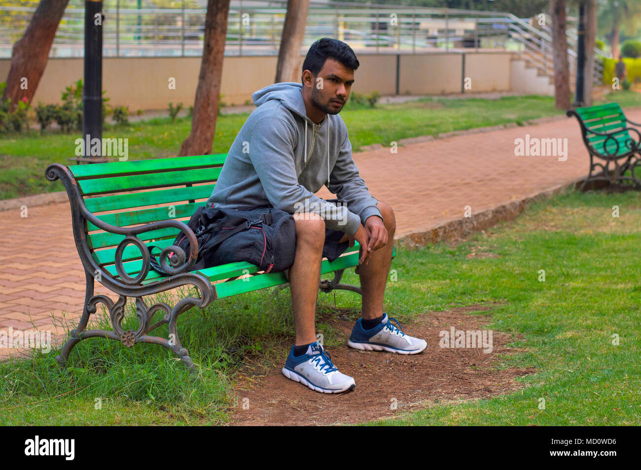 Young sportsman sitting on a wooden bench in a park Stock Photo