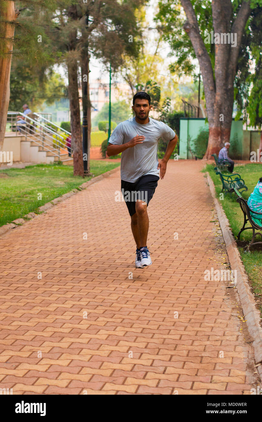 Young guy jogging on a path in a park Stock Photo