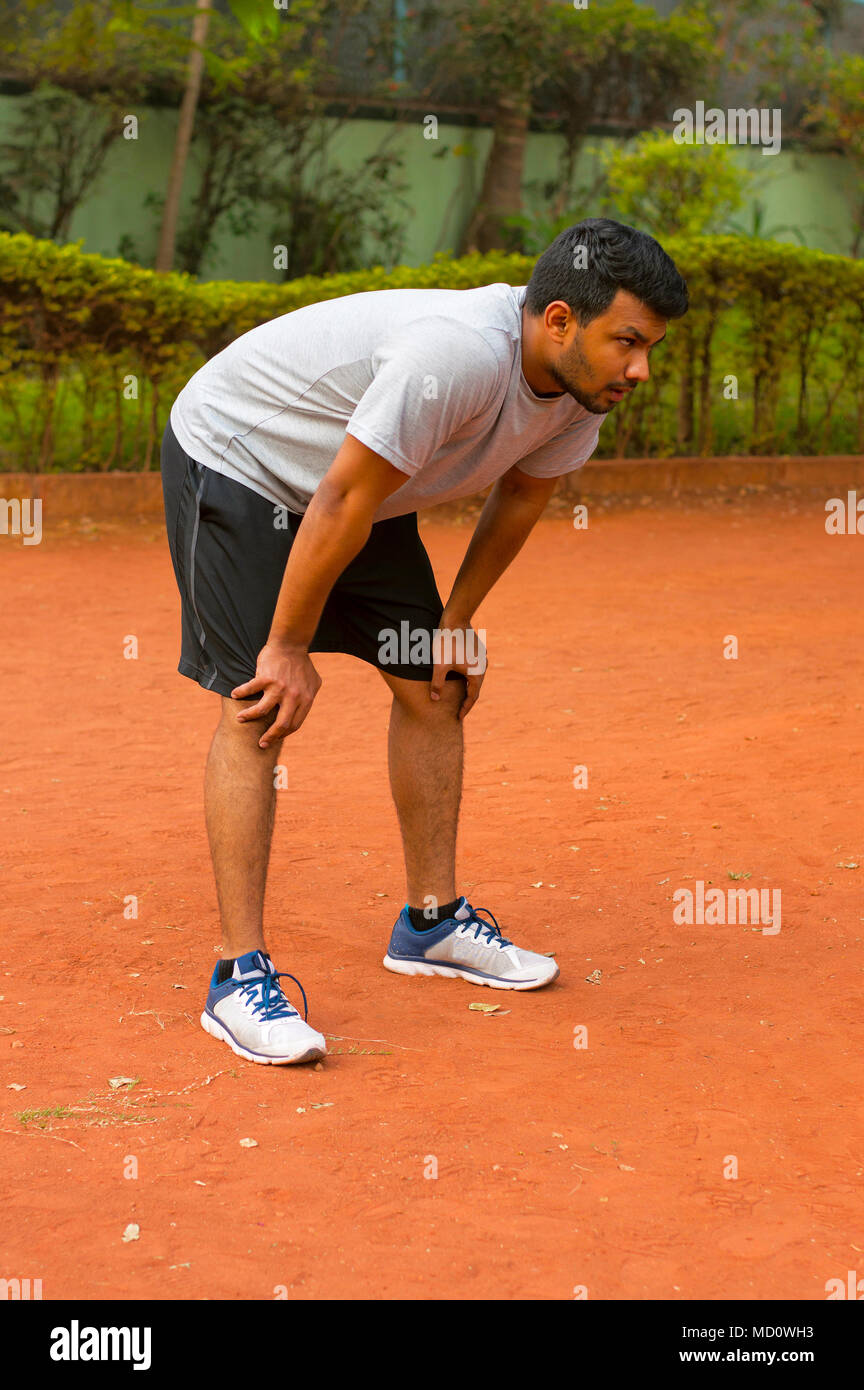 Young guy leaning on his knees after jogging Stock Photo