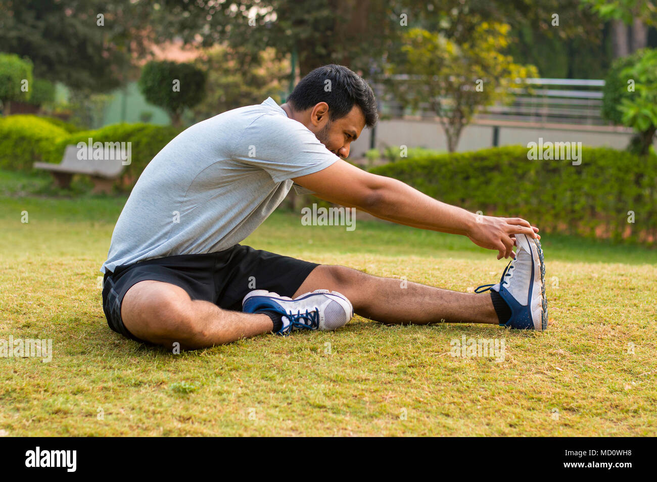 Young guy doing stretching exercise in a park Stock Photo