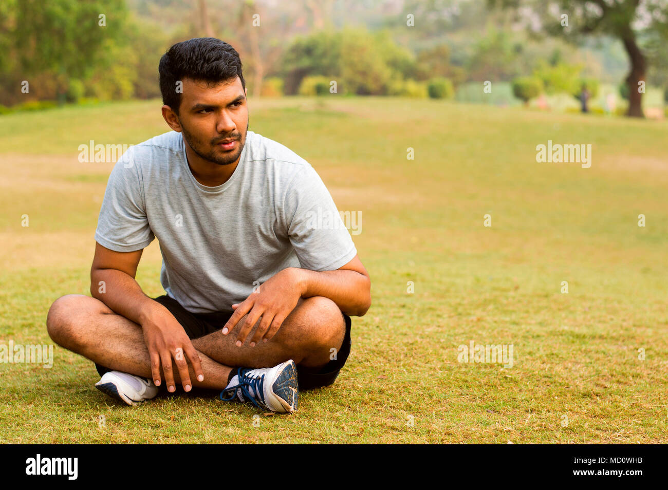 Young guy sitting and taking rest after morning exercise Stock Photo