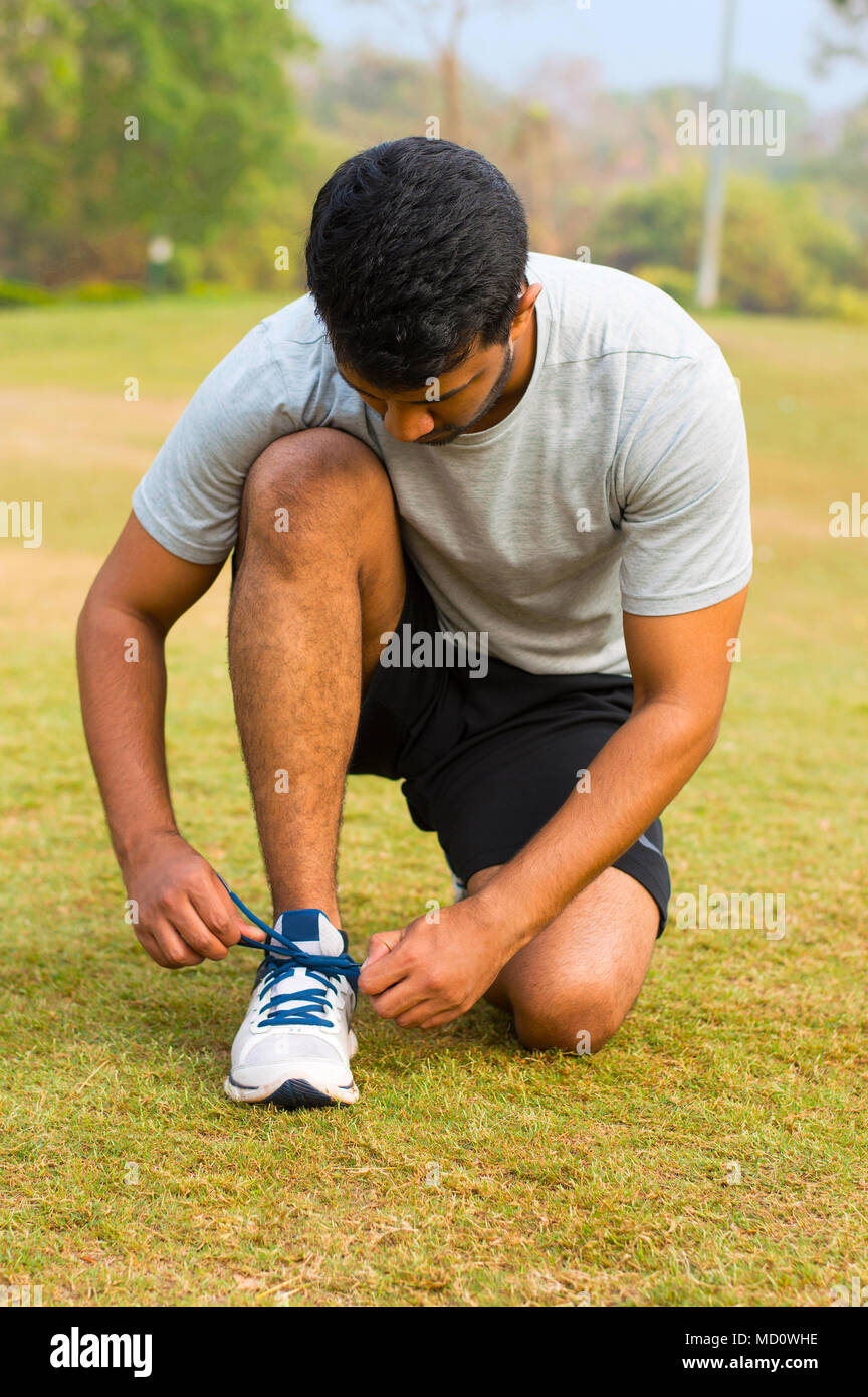 Young guy tying shoe laces and getting ready to run Stock Photo