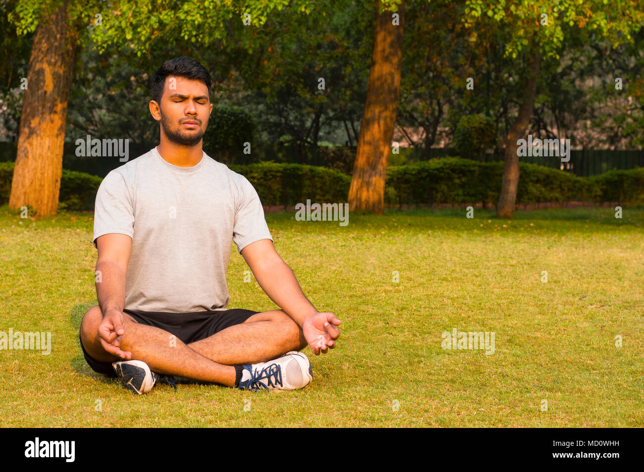 Young guy doing yoga lotus pose in a park Stock Photo