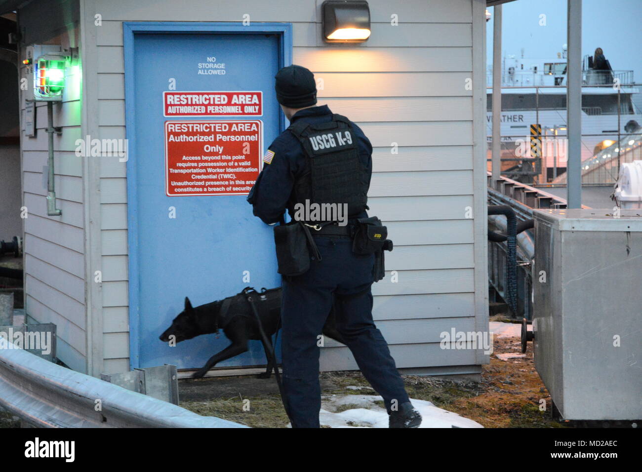 Canine Luna and his handler Petty Officer 1st Class Elliott Felix, a member of Coast Guard Maritime Safety and Security Team Seattle (91101), conduct a sweep of the Alaska Marine Highway System ferry terminal in Juneau, Alaska, March 12, 2018. The Coast Guard, Alaska State Troopers and Juneau Police Department partnered together during the law enforcement operation to detect and deter illegal activity on Alaska's waterways. U.S. Coast Guard photo by Lt. Brian Dykens. Stock Photo