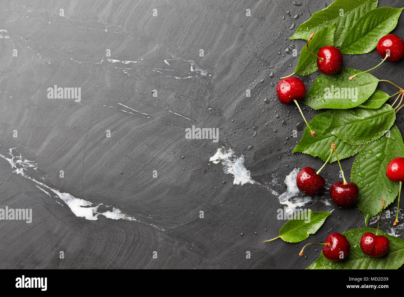 Frsh sweet cherries with leaves on black stone, top view Stock Photo