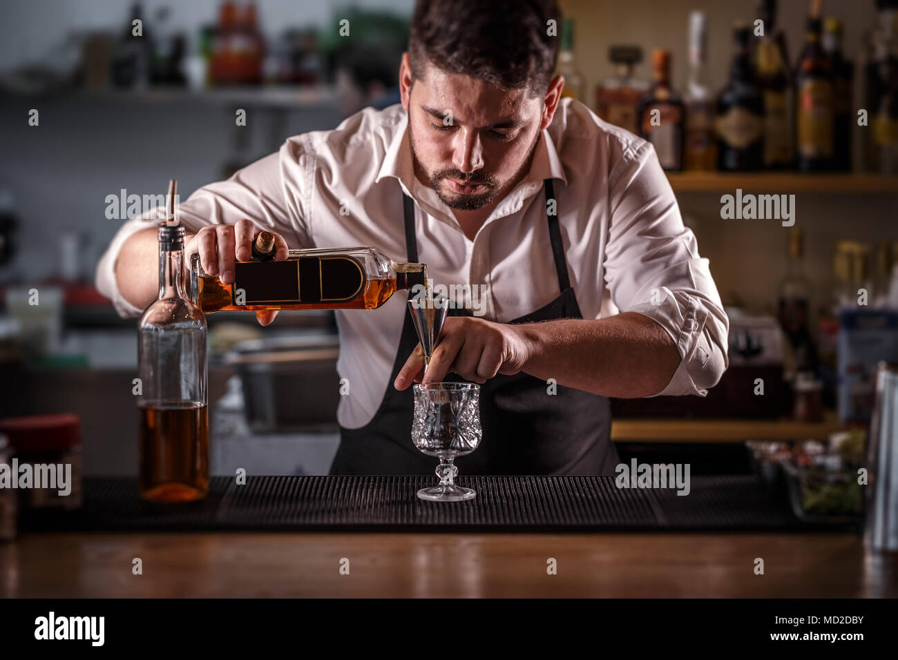 Bartender preparing alcohol cocktail drink, pouring rum filling a jigger Stock Photo