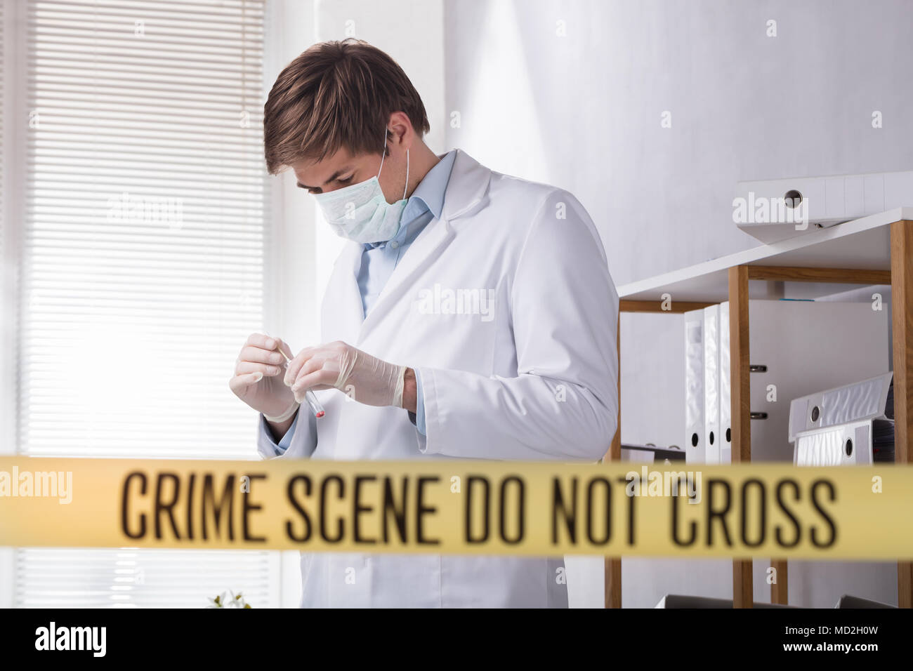 Crime Scene Do Not Cross Tape In Front Of Forensic Expert Looking For Evidence Stock Photo