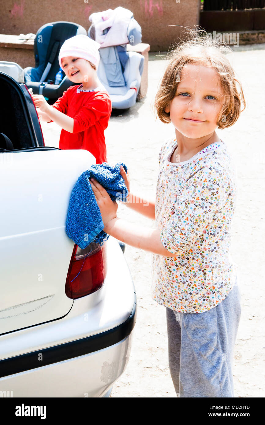 Sisters helping out with washing and cleaning a car. Stock Photo