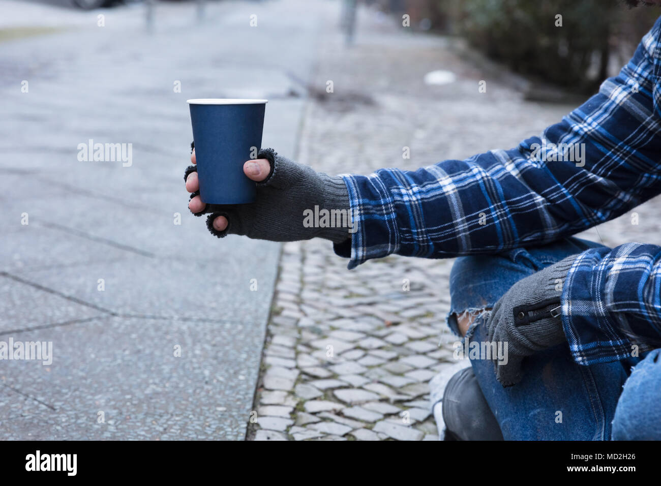 Beggar's Hand Wearing Gloves Holding Disposable Cup Stock Photo