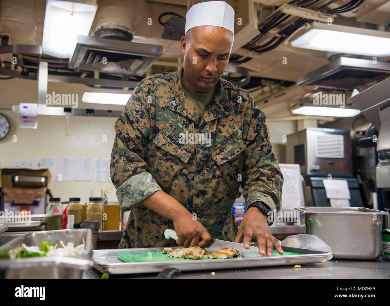 PHILIPPINE SEA (March 26, 2018) Staff Sgt. Arthur Fisher, from Manhattan, N.Y., dices up chicken for a meat and vegetable soup for dinner aboard the amphibious dock landing ship USS Ashland (LSD 48). Ashland, part of the Wasp Expeditionary Strike Group (ESG), with embarked 31st MEU, is operating in the Indo-Pacific region to enhance interoperability with partners, serve as a ready-response force for any type of contingency, and advance the Up-Gunned ESG concept. Stock Photo