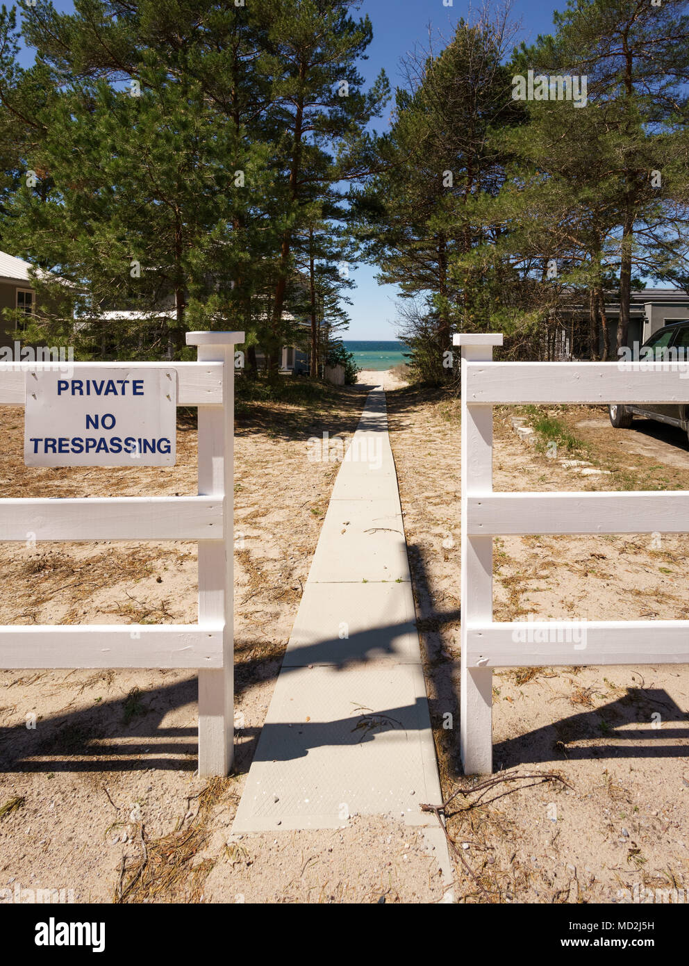 No trespassing sign on fence by footpath leading to sea, Ontario, Canada Stock Photo