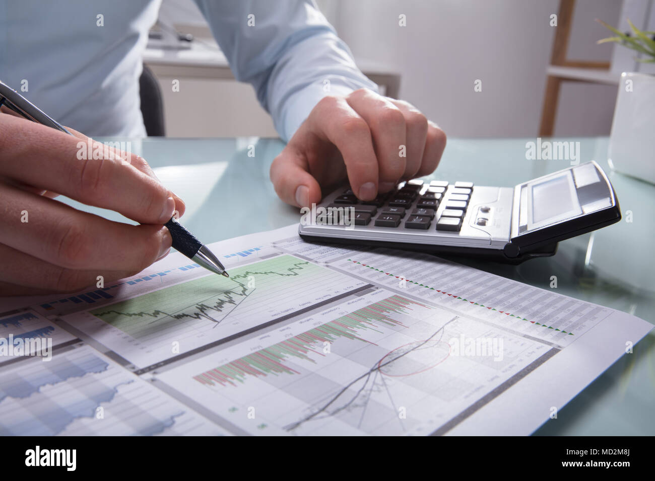 Photo Of Businessperson's Hand Analyzing Graph Using Calculator Stock Photo