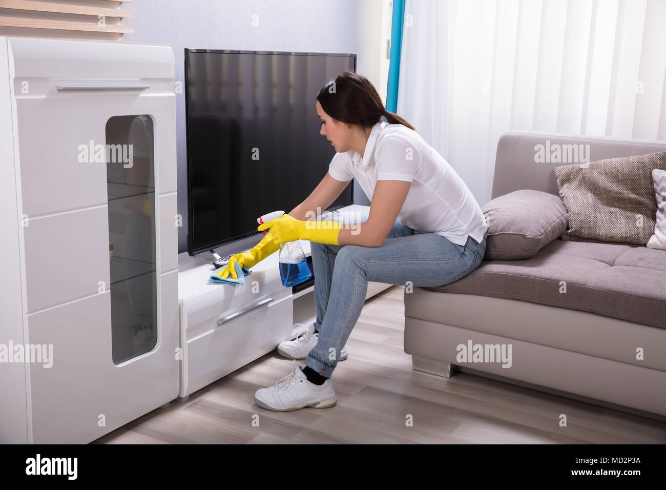 Side View Of A Young Female Janitor Cleaning Furniture At Home Stock Photo